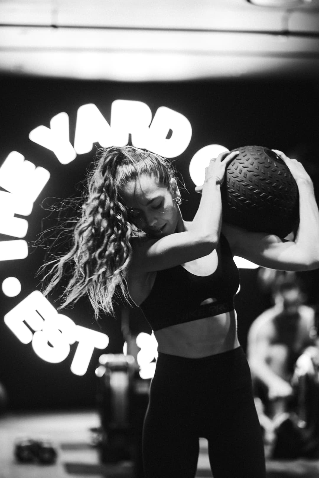 Female member training during a turf conditioning session in front of the iconic LED Yard Gym sign at The Yard Gym Somerton Park, South Australia.